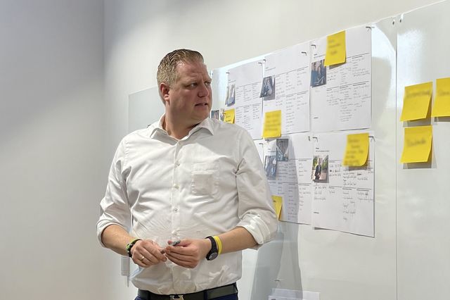 Eine Person steht vor einem Whiteboard mit Personas und Post-Its.
