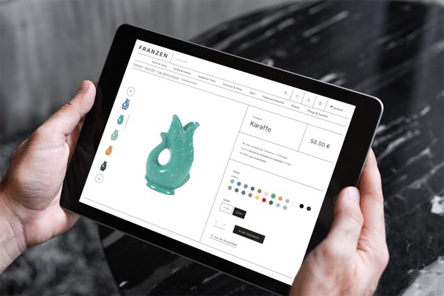 Hände halten ein iPad mit der Darstellung des Onlineshops.