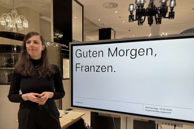 Eine Person präsentiert das neue Corporate Design auf einem großen Screen innerhalb des Ladenlokals.