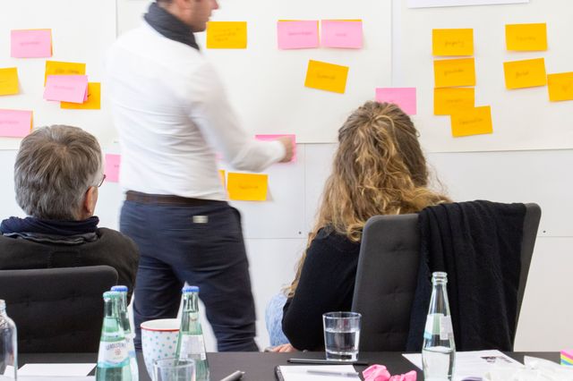 Anteon-Mitarbeiter sitzen, beziehungsweise stehen vor einem Whiteboard