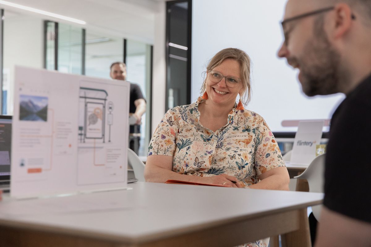 Persönlicher Austausch und konstruktives Feedback bilden die Grundlage erfolgreicher UX-Workshops und nutzerzentrierter Produktentwicklung. Eine Teilnehmerin tauscht sich im UX-Workshop mit dem Team aus und diskutiert Anforderungen sowie Nutzerbedürfnisse in offener Arbeitsatmosphäre.