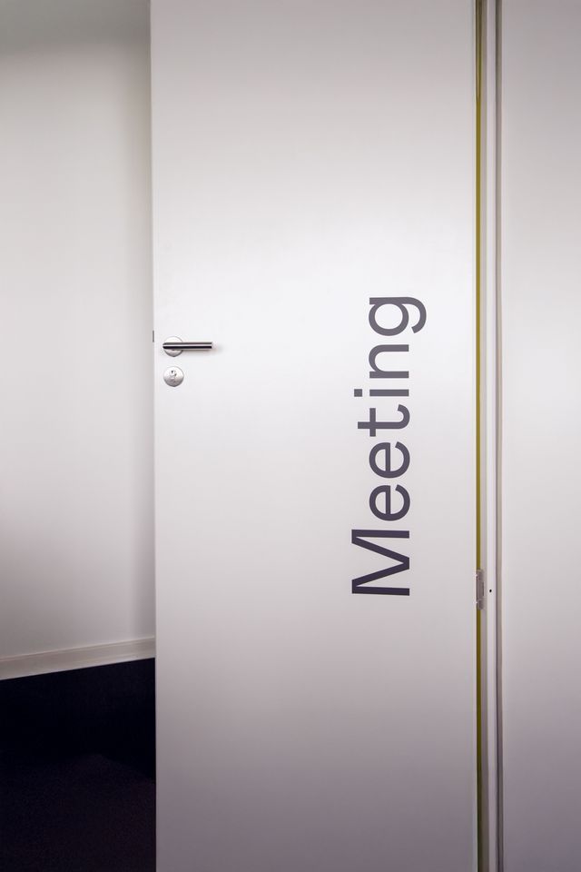 Die Türbeschriftung unterstützt die Orientierung in den Büroräumen. Weiße Tür mit vertikaler Beschriftung „Meeting“ im Büro von Haavest.