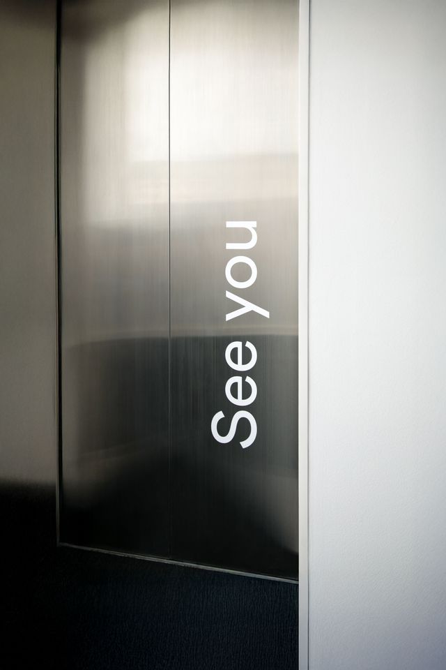 Markante Beschriftungen stärken das Markenerlebnis im Büroalltag. Aufzugstür mit vertikal angebrachter Beschriftung „See you“ als Teil des Interior Brandings.