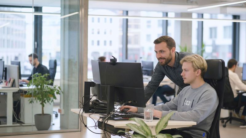 Das neue Corporate Design von Heringer. Zwei Mitarbeiter tauschen sich aus.