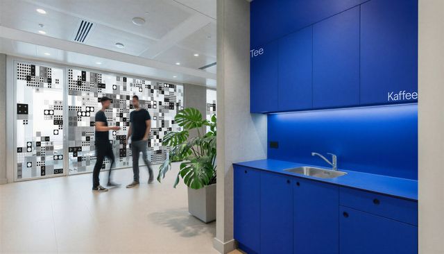 Eine blaue Küche, zwei Mitarbeiter tauschen sich aus.