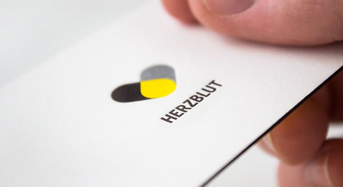 Eine Person hält eine Visitenkarte mit Farbschnitt und Tiefprägung in der Hand