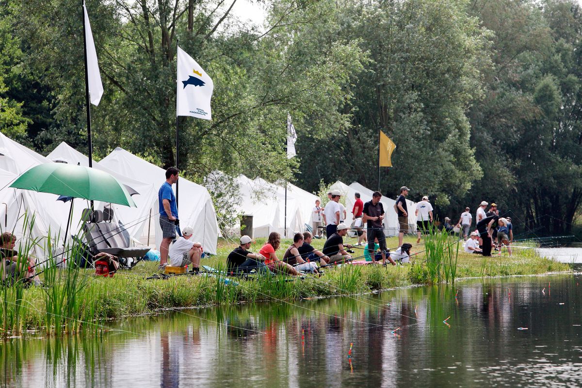 Menschen sitzen an einem See und fischen