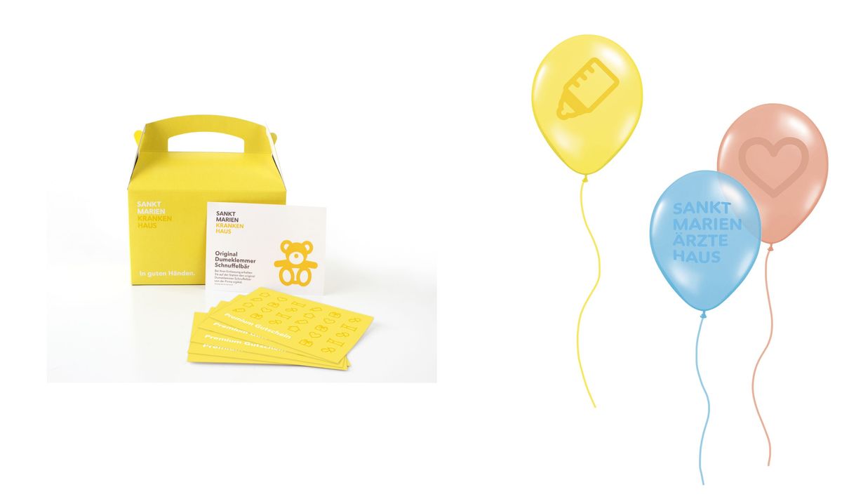 Eine Geschenkbox für frisch gebackene Eltern ist neben drei farbigen Luftballons zu sehen