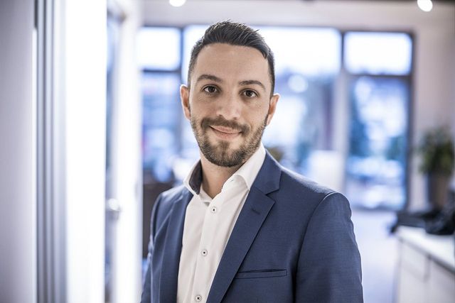 Porträt eines Mannes im Business-Outfit, der freundlich in die Kamera blickt, im modernen Büro.