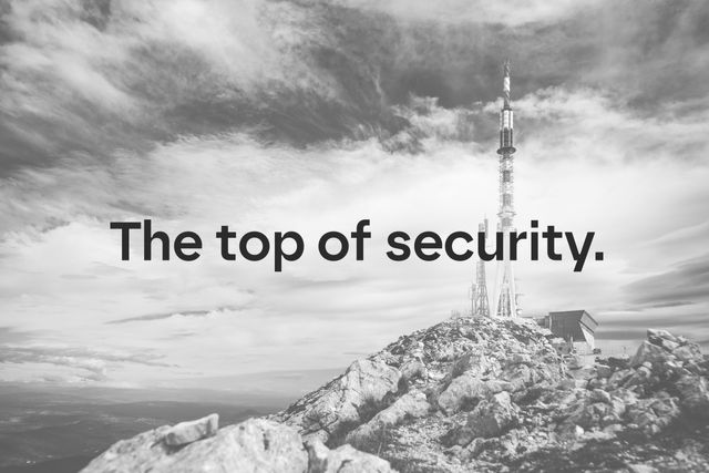 Schwarzweißaufnahme eines Berggipfels mit Sendemast und dem Schriftzug „The top of security.“ im Vordergrund.
