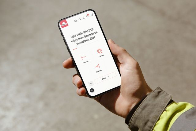 Person hält ein Smartphone mit einem digitalen Selbsttest zur Bewertung kritischer Infrastruktur-Standorte.