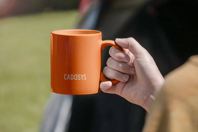 Tasse mit Cadosys-Logo auf orangefarbenem Hintergrund
