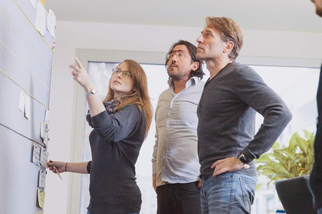 Mitarbeiter von Cologne Intelligence stehen vor einer Pinnwand