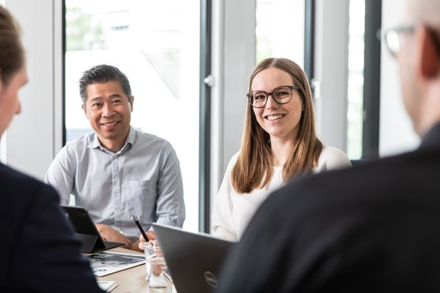 Die Mitarbeiter von Copart besprechen sich. Mitarbeiter sitzen an einem Tisch und unterhalten sich.