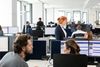 Ansicht eines Büroumfeldes, verschiedene Mitarbeiter sehen sich an.