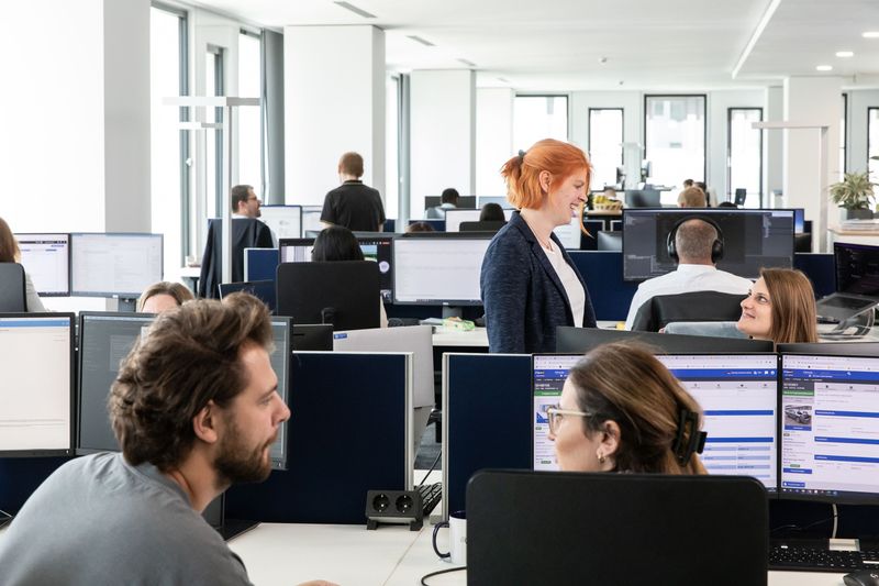 Ansicht eines Büroumfeldes, verschiedene Mitarbeiter sehen sich an.