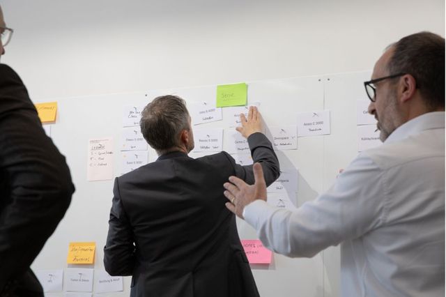 Mitarbeiter hängen im Workshop Post-Its an die Magnetwand.