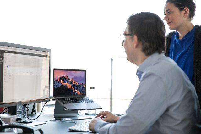 Gespräch zwischen zwei Kollegen mit Blick auf den Computer, auf dem ein Graph und eine Tabelle angezeigt werden