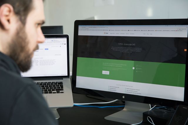 Entwickler arbeitet am Laptop und Bildschirm und hat eine Website über ein Content Management System geöffnet