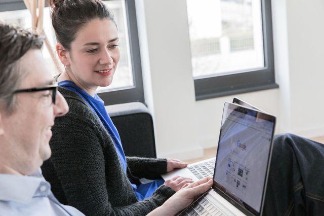 Zwei Kollegen besprechen sich mit Blick auf den Laptop, auf dem Google geöffnet ist