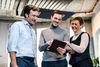 Ansicht von zwei Mitarbeitern und einer Mitarbeiterin die gemeinsam auf ein iPad schauen.