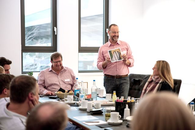 Geschäftsführer hält im Workshop ein Bild der Bilderbox hoch