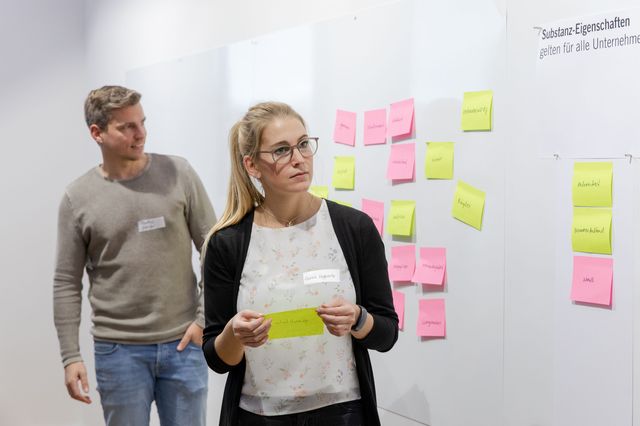 Mitarbeiter von Extruder Experts ordnen Notizzettel mit Markenwerten an eine Pinwand