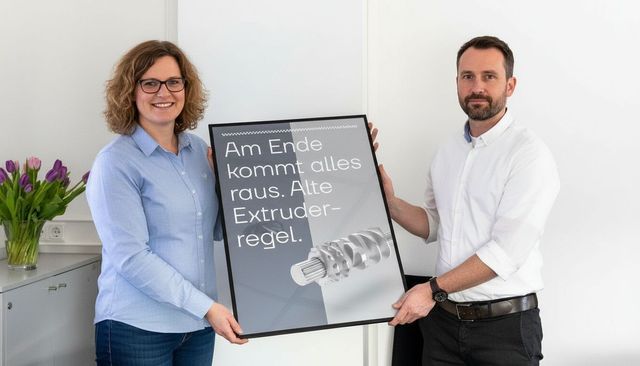 Zwei Mitarbeiter halten ein Plakat hoch.