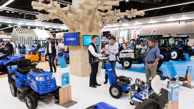 Messestand mit großem Holzbaum, Fernsehen mit Imagefilmen sowie  Traktoren mit dazugehörigen Aufstellen mit Produkbroschüren