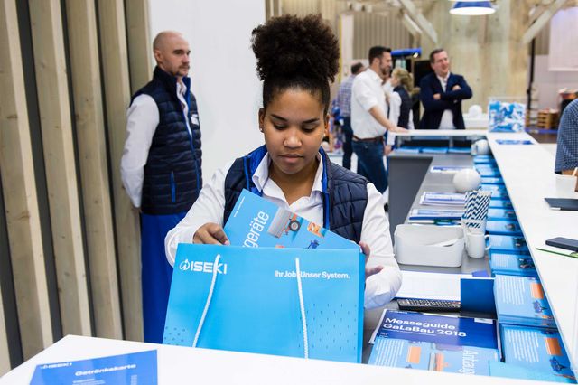 Iseki-Mitarbeiterin packt am Messestand die Anbaugerätebroschüre in eine Tüte