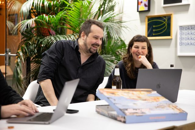 Zwei Personen sitzen an einem Tisch und besprechen ein Projekt, welches auf dem Notebook dargestellt wird