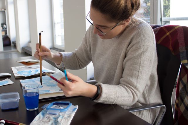 Designerin malt blaue Aquarellelemente
